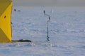 Process of ice fishing, group of fishermen on ice near tent shelter, with equipment in a winter snowy day, tents and ice auger on