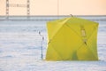 Process of ice fishing, group of fishermen on ice near tent shelter, with equipment in a winter snowy day, tents and ice auger on Royalty Free Stock Photo