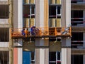 The process of insulating external walls in a multi-storey building under construction. Workers in an orange Royalty Free Stock Photo