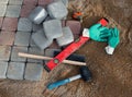 Process of laying paving stones in layers. Brick pathway paving equipment top view: hammer, level, bricks, gloves, bucket with