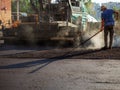 Process of leveling the asphalt manually using a special rake.