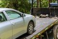 The process of loading a damaged, broken car on a tow truck working in a towing company