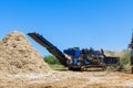 In process of loading roots trees into an industrial shredder machine, forest mulcher chopped a wood log. Royalty Free Stock Photo