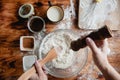 The process of making baking dough in a glass bowl on a wooden table sprinkled with flour. Top view. Flat layout. Royalty Free Stock Photo