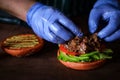 Process of making burger. chef hands in gloves cooking beefburger with avocado