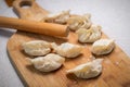 Process of making chinese dumplings. Raw dough and rolling pin on wooden chopping board Royalty Free Stock Photo