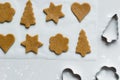 The process of making gingerbread different shaped cookies with rolling pin and sprinkled flour on a light gray background