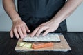 Process of making maki sushi. Cook chef hands preparing rolls with cheese, avocado and sesame seeds on wooden board Royalty Free Stock Photo