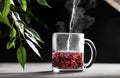 The process of making red tea, boiling water is poured into a transparent mug on a dark background