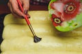 Process of making strudel pie, woman lubricates egg yolk the dough.