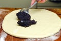 Process of making strudel pie, woman spoon puts poppy stuffing on the dough, wooden board.