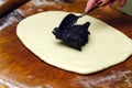 Process of making strudel pie, woman spoon puts poppy stuffing on the dough, wooden board.