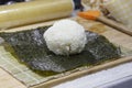 The process of making sushi and rolls with cucumber. Rice on nori sheet