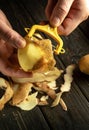 The process of manually peeling potatoes on the kitchen table. Close-up of a man hands with a potato peeler while working Royalty Free Stock Photo