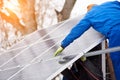 Process of mounting blue solar modules on the roof of modern building during winter snowy time. Royalty Free Stock Photo