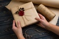 Process of package gift wrapped in craft paper, tied with string and glued wax seal on wooden black background