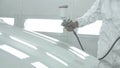 Process of painting a white car in a spray booth. Man using a spray gun Royalty Free Stock Photo