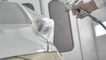 Process of painting a white car in a spray booth. Man using a spray gun Royalty Free Stock Photo