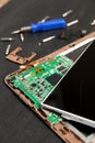 Process of PC Tablet device repair near screwdriver and bit on black wooden background. Disassembled. Broken glass, screen destroy Royalty Free Stock Photo