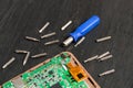 Process of PC Tablet device repair near screwdriver and bit on black wooden background. Disassembled. Close up.