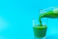 Process of Pouring from Bottle to Glass of Green Fresh Smoothie from Leafy Greens Vegetables Fruits. Apples Bananas Kiwi Zucchini Royalty Free Stock Photo