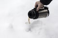 the process of pouring coffee into a disposable glass in winter in a snowdrift in nature Royalty Free Stock Photo