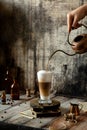 Process of pouring coffee in latte glass stands on wooden boards on grey rustic table Royalty Free Stock Photo