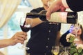 Process of pouring red wine into glasses above the festive table. Man fills the glasses with alcohol to drink toasts at a restaura Royalty Free Stock Photo