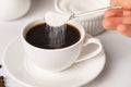 The process of pouring white sugar from a spoon into a white cup of coffee. Sugar addict, diabetes. Royalty Free Stock Photo