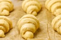 Process of preparation of dessert from yeast dough. Raw croissants on a baking paper. Concept of traditional french or Royalty Free Stock Photo