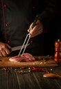 The process of preparing a beef steak by the hands of a chef. Spices and rosemary on the kitchen table in a restaurant for Royalty Free Stock Photo