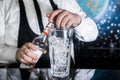 The process of preparing a cocktail. Professional bartender with a bottle of syrup in his hands next to a glass of ice cubes on Royalty Free Stock Photo