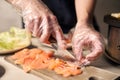 Process of preparing components for food. Slicing with knife pieces of fish on cutting board for cooking food. Close up