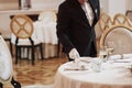 Process of preparing place for special visitors. Waiter in classical wear works on the servering Royalty Free Stock Photo