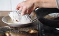 The process of preparing river fish crucian carp for frying in a pan.Elderly woman`s hand rolls the fish in flour Royalty Free Stock Photo