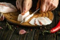 The process of preparing sandwiches for a snack from lard and garlic in the kitchen. Chef hands use a knife to cut pork lard on a