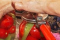 The process of preserving tomatoes for the winter. Women's hands close the lids of jars with ripe red juicy tomatoes with a