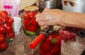 The process of preserving tomatoes for the winter. Women's hands close the lids of jars with ripe red juicy tomatoes with a