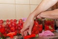 The process of preserving tomatoes for the winter. Women's hands close the lids of jars with ripe red juicy tomatoes with a