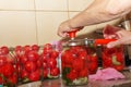 The process of preserving tomatoes for the winter. Women's hands close the lids of jars with ripe red juicy tomatoes with a