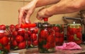The process of preserving tomatoes for the winter. Women's hands close the lids of jars with ripe red juicy tomatoes with a