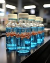 Process of producing cosmetics. Many glass bottles with yellow blue liquid standing near conveyor on factory. Row line Royalty Free Stock Photo