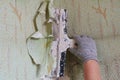 The process of removing old worn out unattractive green from the wall with the help of available tools and a spatula, hands,