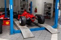 The process of repairing and restoring a red Ferrari Formula 1 car at a pitstop in the service station or a repair workshop on a