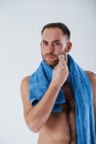 Process of taking care of sensitive skin on the face. Man with blue towel stands against white background in the studio Royalty Free Stock Photo