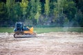 Process of terraforming changing face of the earth due to activities of people. Bulldozer mounts mound or hill of sand heaps lake