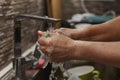 Process of washing cloth under running water above sink full of dishes