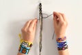Process of weaving knot for DIY friendship bracelet. Female hands with many handmade bracelets on wrists. step by step.