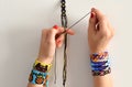 Process of weaving knot for DIY friendship bracelet. Female hands with many handmade bracelets on wrists. step by step.