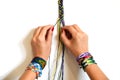 Process of weaving knot for DIY friendship bracelet Pigtail. Female hands with many handmade bracelets on wrists. step by step. Wh